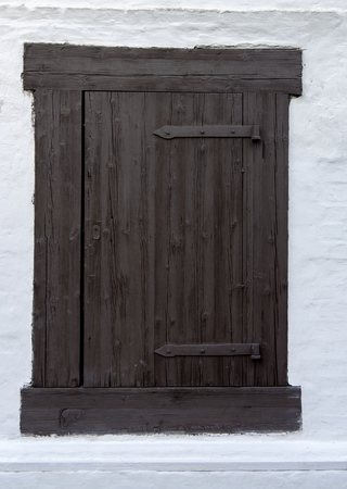 Old window closed with wooden shutters in white wallの写真素材