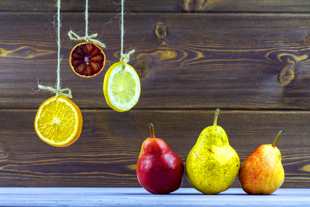Hanging on ropes slices of lemon, orange and lime. On the table lay a ripe pearsの写真素材
