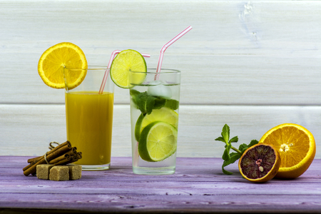 A glass of orange juice, a glass of Mojito. Sliced orange, sugar, mint, cinnamonの写真素材