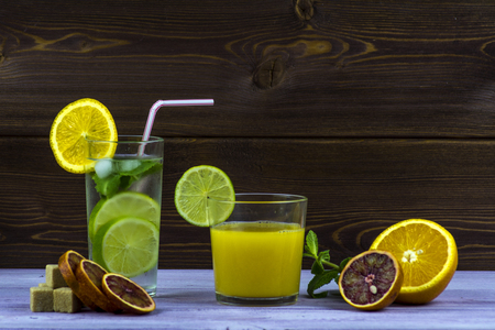 A glass of orange juice, a glass of Mojito. Sliced orange, sugar, mint, cinnamonの写真素材
