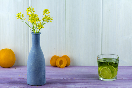 Vase with field yellow flowers, apricots on the table and a glass of Mojitoの写真素材