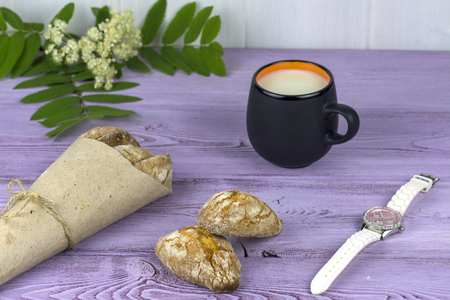 On the table, spring flowers, a mug of milk and sweet homemade cookies and women's watches.の写真素材