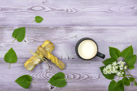 Black mug with milk. Homemade sweet cookies. Sprig and white lilac flowers on the table.の写真素材