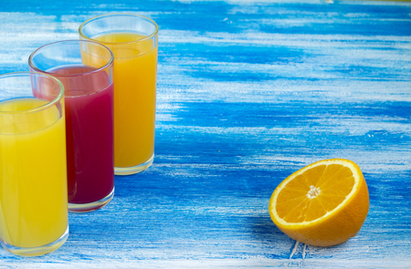 Three glasses of soft drinks are on a blue background. Slices of an orange. Summer drinksの写真素材