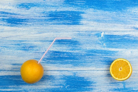 Two oranges with a cocktail straw. Summer drinks and healthy lifestyle. Blue background の写真素材