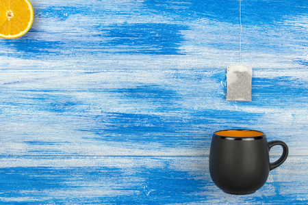 The Cup of tea on a blue background. Tea bag and orange slices.の写真素材