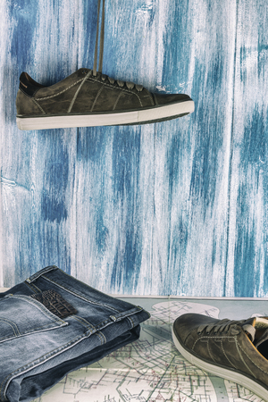 Collecting to travel. Jeans, passport, sneakers and a map on a wooden background.の写真素材