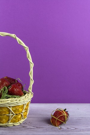 Basket with strawberries is on the table. One berry lies nearby.の写真素材