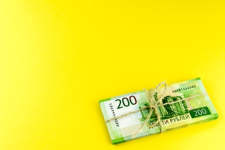A bundle of money. Russian cash. A bundle tied with a rope. Denominations in 200 rubles. On a yellow...