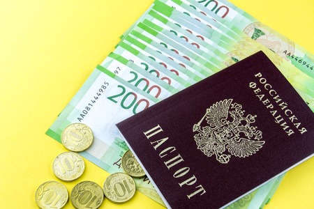Russian money cash and a few coins. Denominations in 200 rubles. Russian passport on a yellow backgroundの写真素材