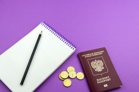 Russian passport and several coins. Notepad for entries and pencil on an purple backgroundの写真素材