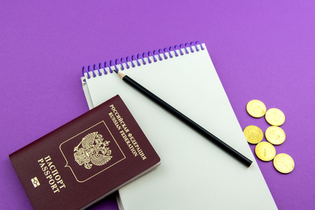 Russian passport and several coins. Notepad for entries and pencil on an purple backgroundの写真素材