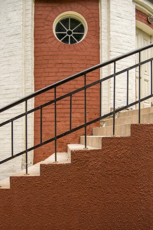 Stairs in a brick house. Round window in the wall. Railing.の写真素材