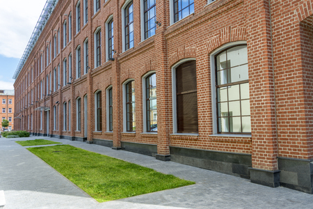 Office building in loft style. Large Windows. Red brick wall. Grass in front of the buildingの写真素材