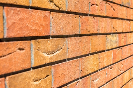 Red brick wall. Decorative brick with artificial defects and cracks. Angle view with perspective....