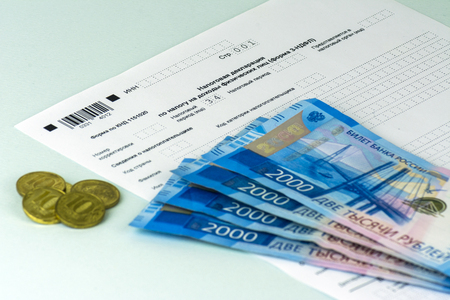 Russian annual tax Declaration of taxes of individuals. The Form 3-NDFL. A few Russian notes and coins are on the sheet of the Declaration. Blue backgroundの写真素材