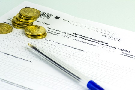 Russian annual tax Declaration of taxes of individuals. The Form 3-NDFL. A few Russian coins are on the sheet of the Declaration. Blue backgroundの写真素材