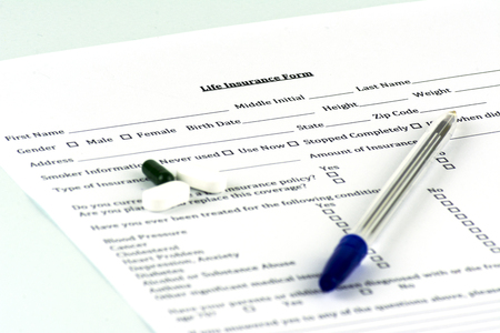 Life insurance form. A few pills and a pen on the sheet. Blue backgroundの写真素材