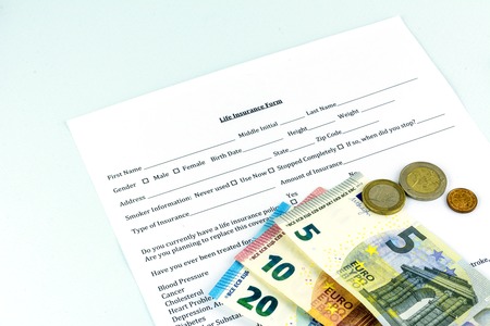 Life insurance form. A few pills and bills on the sheet. Cash banknote euro. Blue backgroundの写真素材