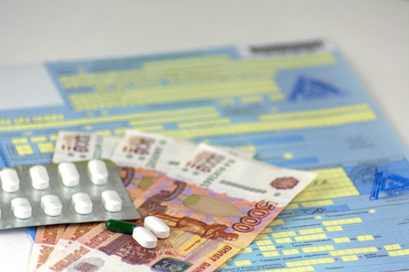 Russia. Russian sick leave with seals. The bottle of pills and a few pills in bulk. Russian money-banknotes of 5000 rubles. Focus on the nearest pills.の写真素材