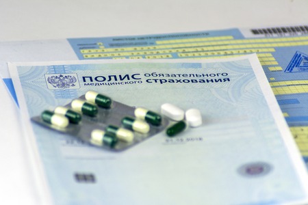 Russia. The Russian policy of Compulsory Health Insurance and sick leave with seals. The bottle of pills and a few pills in bulk. Focus on the nearest pills.の写真素材
