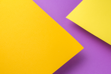 Two sheets of yellow and orange paper soar above the purple background.の写真素材