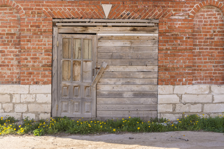 Boarded up wooden door to an old warehouse in a brick wall.の写真素材