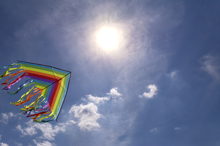 Colorful kite flying in blue sky background sky. Bright sun.の写真素材