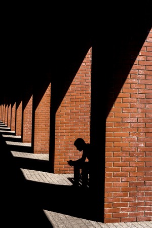 The silhouette of a man sitting on a bench in the loft.の写真素材