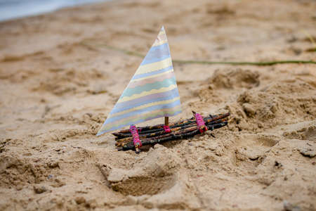 One toy boat on sandy beach A toy sailing ship in the riveの写真素材
