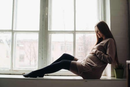 pregnant beautiful woman sitting by the windowの写真素材