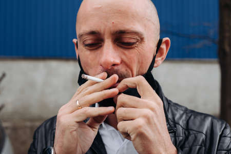 man with mask during COVID-19 pandemic smoking at the streetの写真素材