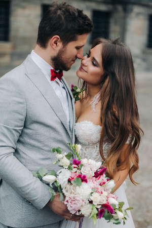 Beautiful bride and groom embracing and kissing on their wedding day outdoorsの写真素材