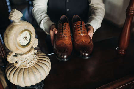 businessman holding shoes in his hands, close-up. Chic interior, vintage clock,の写真素材