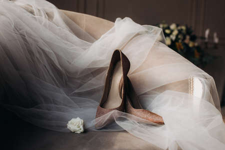 Wedding shoes for newlyweds with a veil close-up lying on a chair, next to a flower, beautiful layout.の写真素材