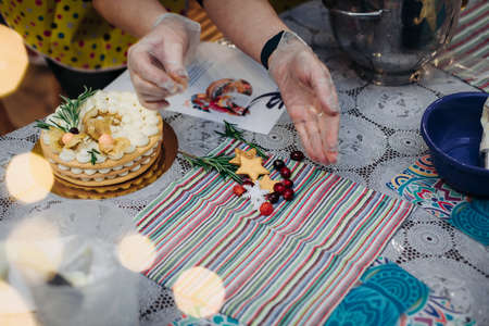 Christmas cake in the form of a wreath.Hands of a female pastry chef decorate a cake with new years...