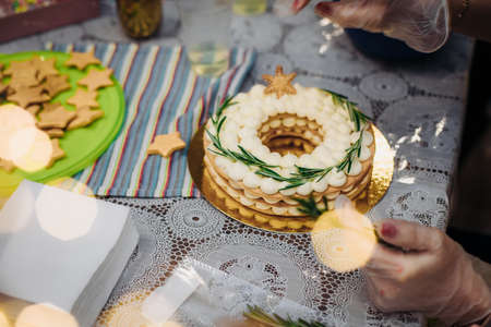 Christmas cake in the form of a wreath.Hands of a female pastry chef decorate a cake with new years edible decor.の写真素材