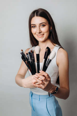 make-up artist's brushes in the hands in the foreground. on a light background, isolated