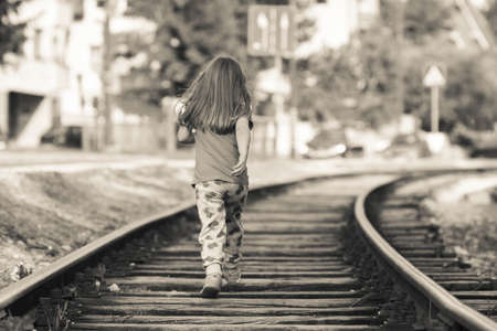 Girl child running on railroad tracksの写真素材