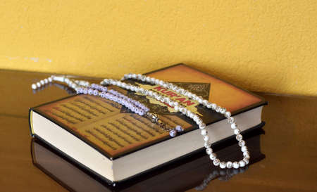 Islamic Muslim prayer holy book with necklace bead rosemary isolated on reflective backgroundの写真素材
