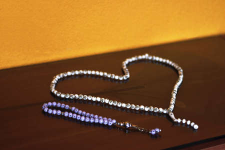 Islamic muslim prayer beads rosemary in a shape of heart isolated on reflective backgroundの写真素材