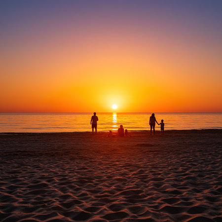 Silhouette of a family walking on the beach at sunset.の素材
