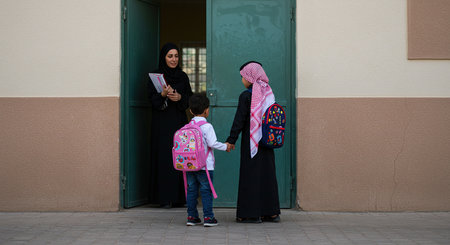 Muslim mother and son with backpacks reading a book in the streetの素材
