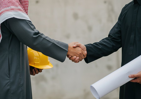 Close-up of engineer and architect shaking hands on construction site.の素材