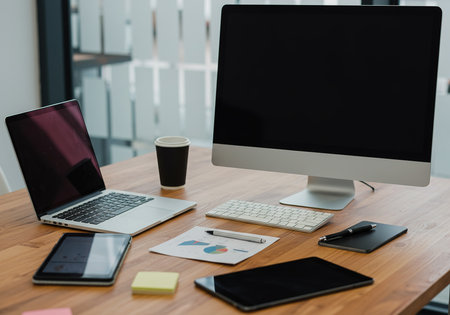 Laptop, tablet, smartphone and coffee cup on wooden table in officeの素材