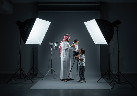 Arabian photographer and his son posing in photo studio with professional lighting equipmentの素材