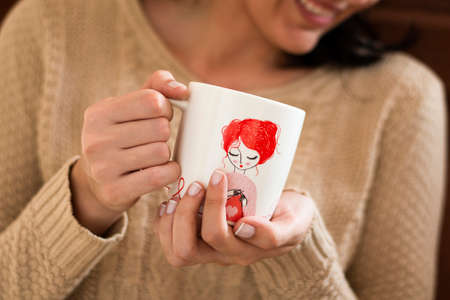 cup of chamomile, woman drinking cup of tea or coffee on wooden backgroundの写真素材