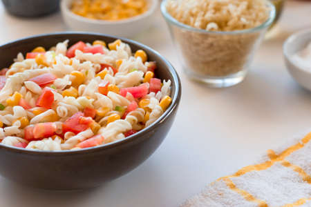 Pasta salad with yogurt and tomato sauce, corn and green onion on white backgroundの写真素材