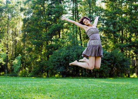 smiling beautiful happy girl jumping in a park in summerの写真素材