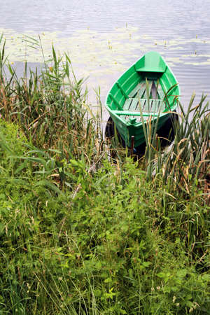 Small green boat on a calm lakeの写真素材